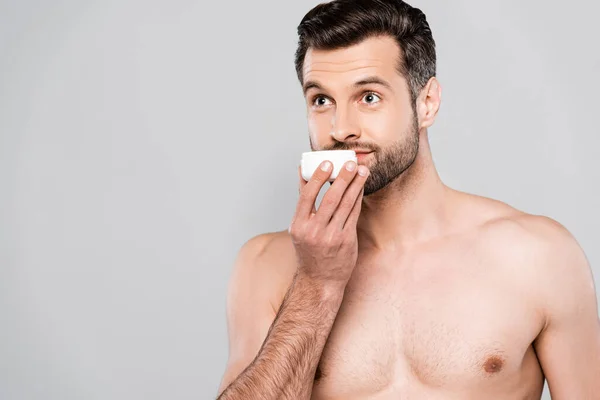 Bärtiger Mann riecht kosmetische Creme isoliert auf grau — Stockfoto