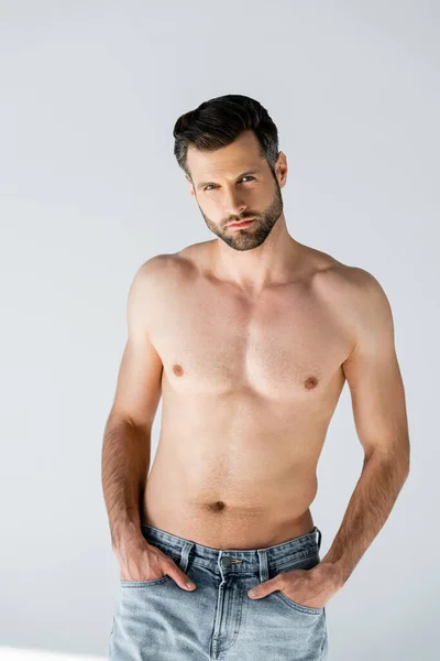 Handsome and shirtless man standing with hands in pockets on grey — Stock Photo