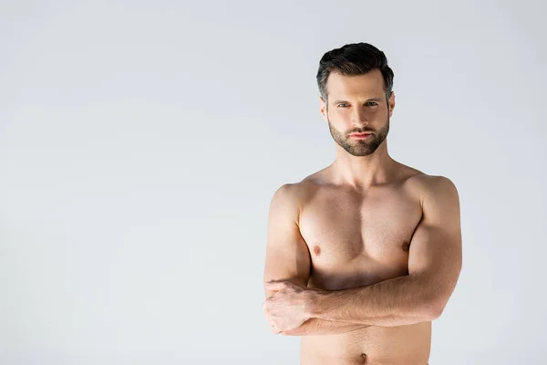 Hombre musculoso de pie con los brazos cruzados aislados en gris - foto de stock