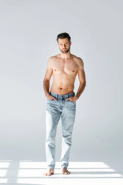 Sole su uomo senza camicia in jeans blu in piedi su grigio — Foto stock