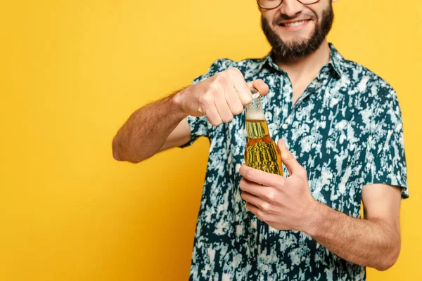 Vista cortada de cara barbudo sorridente abrindo garrafa de cerveja no amarelo — Fotografia de Stock