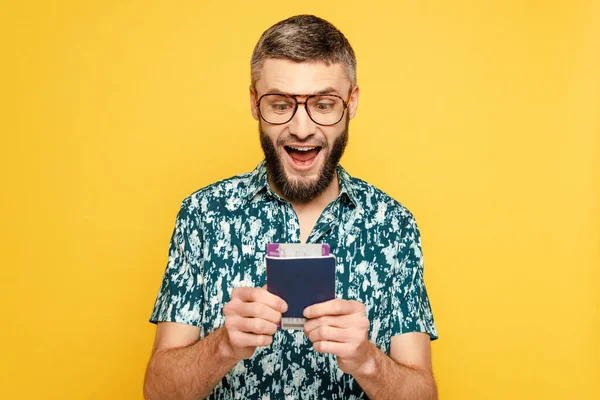 Animado barbudo cara em óculos com bilhete de ar e passaporte isolado no amarelo — Fotografia de Stock