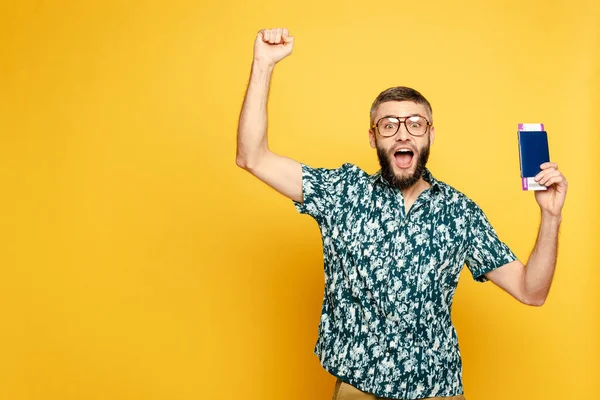 Aufgeregter Bärtiger mit Brille, Flugticket und Pass auf Gelb — Stockfoto