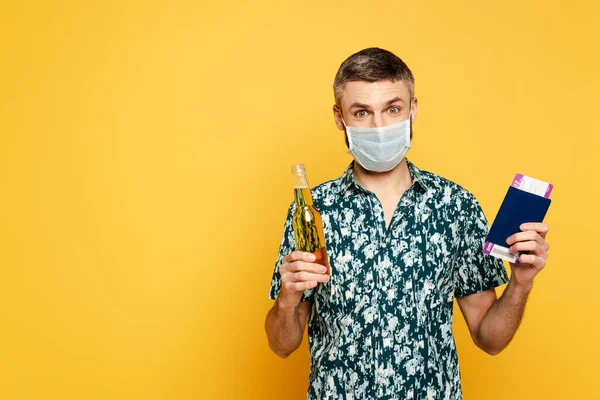 Tipo en máscara médica con cerveza y pasaporte en amarillo - foto de stock