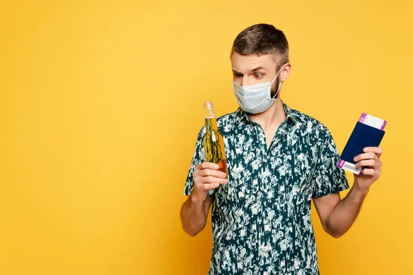 Tipo en máscara médica con cerveza y pasaporte en amarillo - foto de stock