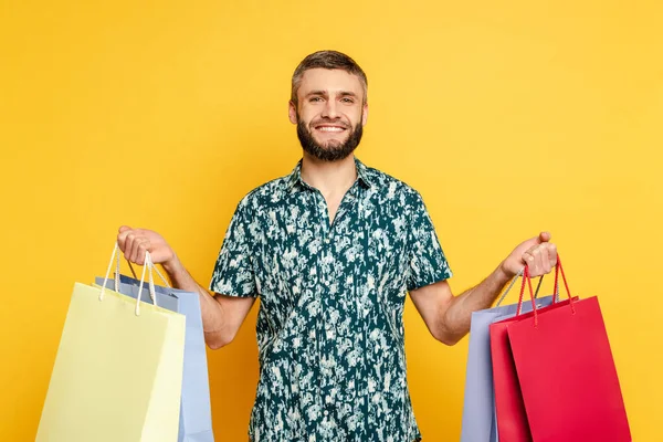 Glücklicher bärtiger Kerl mit Einkaufstaschen auf gelb — Stockfoto