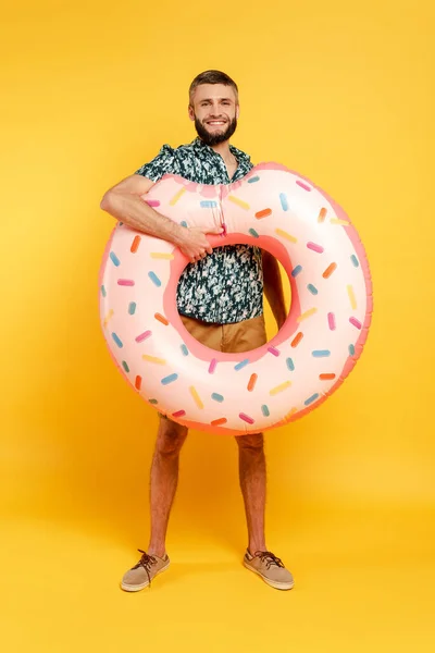 Full length view of happy bearded guy with swim ring on yellow — Stock Photo