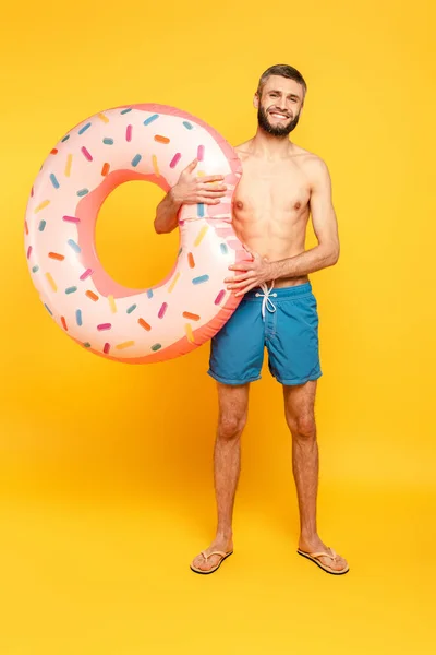 Full length view of happy bearded guy with swim ring on yellow — Stock Photo