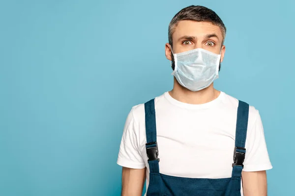 Limpiador en máscara médica sobre fondo azul - foto de stock