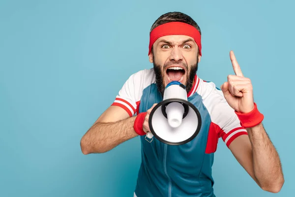 Émotionnel sportif élégant crier dans haut-parleur sur fond bleu — Photo de stock