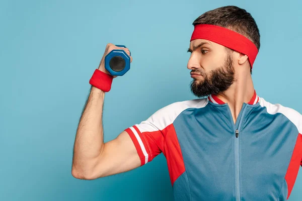 Stylish sportsman exercising with dumbbell on blue background — Stock Photo