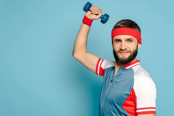 Elegante desportista exercício com haltere no fundo azul — Fotografia de Stock