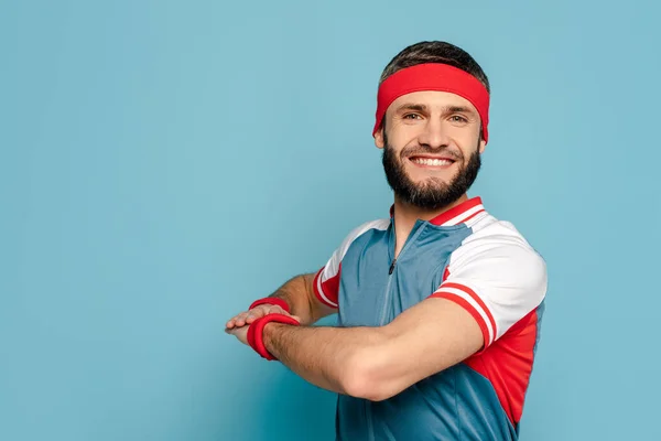 Happy stylish sportsman exercising on blue background — Stock Photo