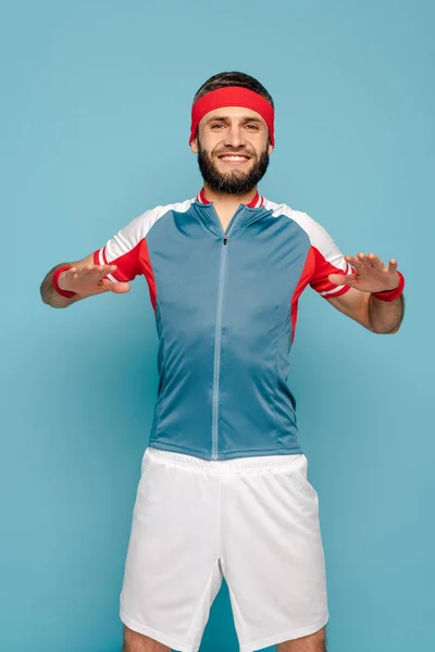 Happy stylish sportsman exercising on blue background — Stock Photo