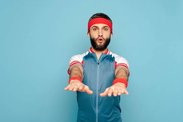 Deportista elegante ejercicio con los brazos extendidos sobre fondo azul - foto de stock