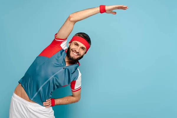 Happy stylish sportsman doing side crunch on blue background — Stock Photo