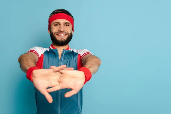 Foco seletivo de desportista elegante feliz aquecendo as mãos no fundo azul — Fotografia de Stock