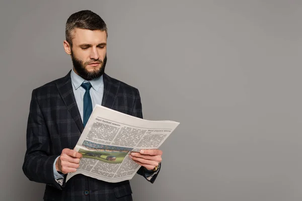 Lächelnder gutaussehender bärtiger Geschäftsmann im Anzug mit Zeitung auf grauem Hintergrund — Stockfoto