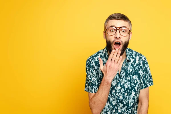 Choqué barbu gars dans des lunettes avec bouche ouverte sur jaune — Photo de stock