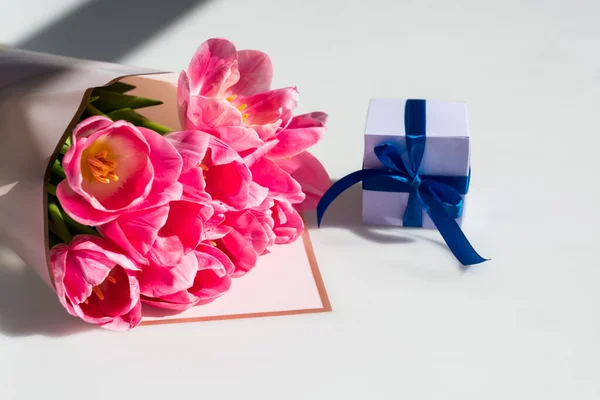 Bouquet of pink tulips near small gift box on white, mothers day concept — Stock Photo