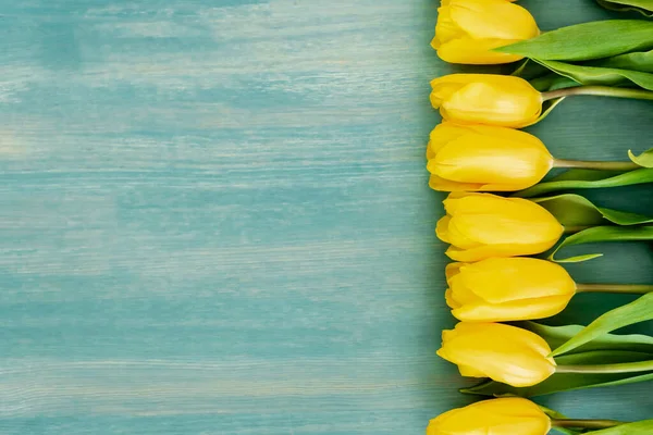 Vista dall'alto di tulipani gialli su superficie strutturata blu, concetto di giorno di madri — Foto stock