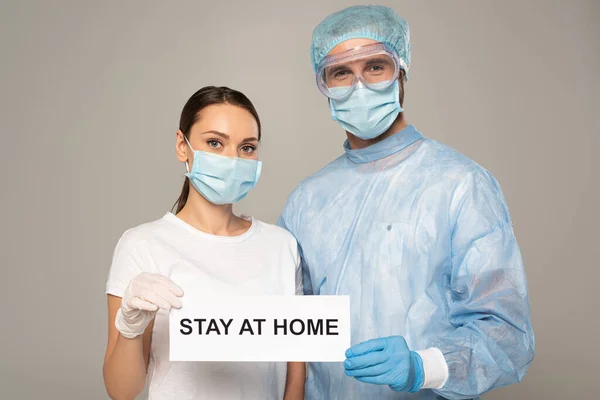 Arzt und Patient halten Karte mit Hausaufenthalt-Schriftzug isoliert auf grau — Stockfoto