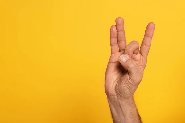 Vista recortada del hombre mostrando una carta del lenguaje de signos cirílico aislado en amarillo - foto de stock