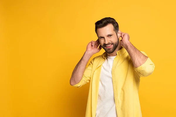 Uomo sorridente che mostra gesto in linguaggio sordo e muto su sfondo giallo — Foto stock