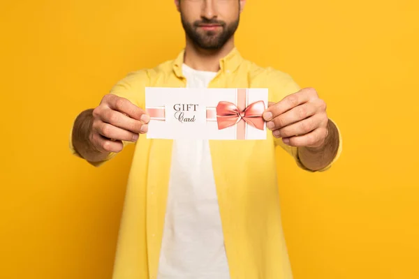 Vista ritagliata di uomo in possesso di carta regalo su sfondo giallo — Foto stock