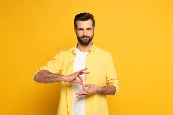 Handsome man showing interpretation sign in deaf and dumb language on yellow background — Stockfoto