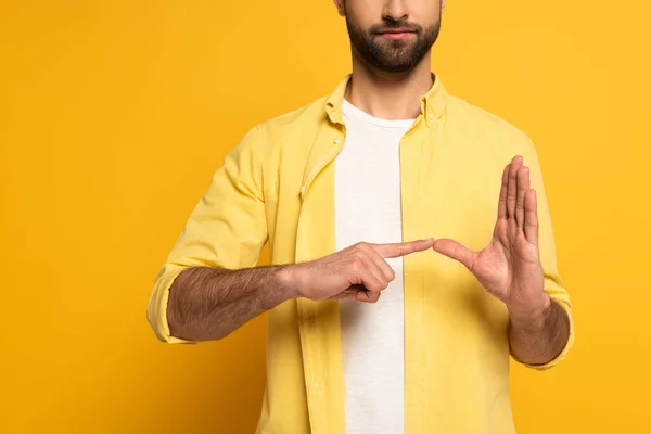 Cropped view of man showing gesture from sign language on yellow background — Stock Photo