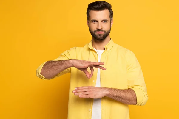 Homme montrant un geste dans un langage sourd et muet sur fond jaune — Photo de stock