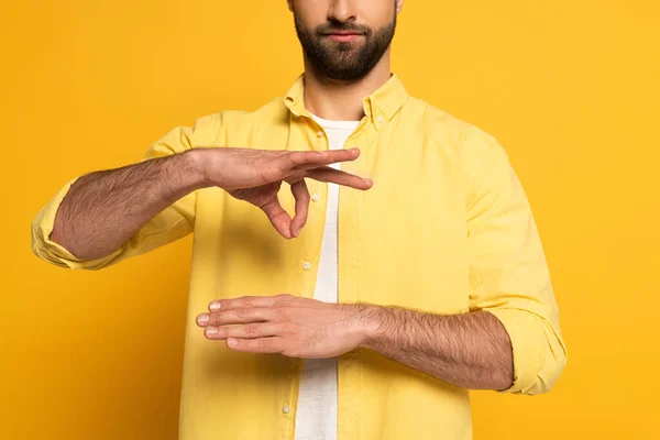 Vista recortada del gesto del hombre mientras se utiliza el lenguaje de señas sobre fondo amarillo - foto de stock