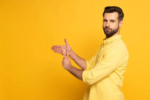Side view of young man showing sign in deaf and dumb language on yellow background — Stockfoto