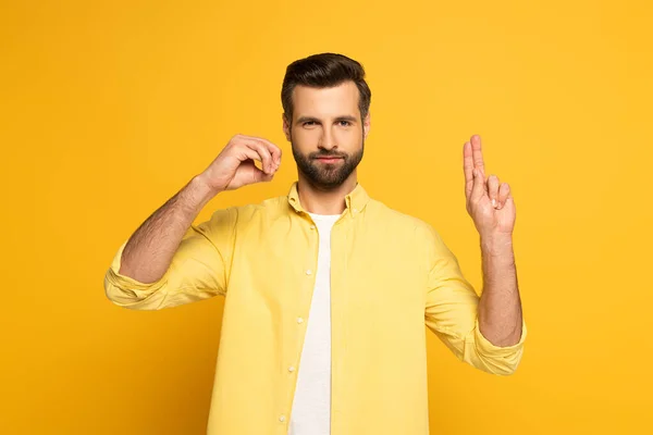 Handsome man showing letters in deaf and dumb language on yellow background — Stockfoto