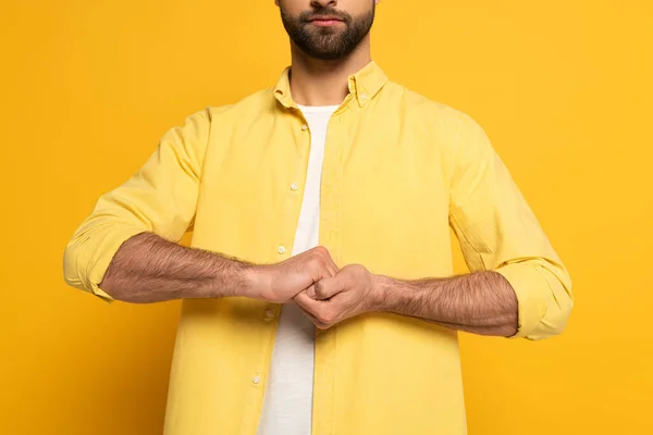 Cropped view of man showing cohesion sign in deaf and dumb language on yellow background — Stock Photo