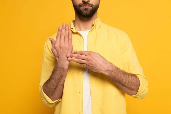 Vue recadrée de l'homme montrant le geste du langage des signes sur fond jaune — Photo de stock