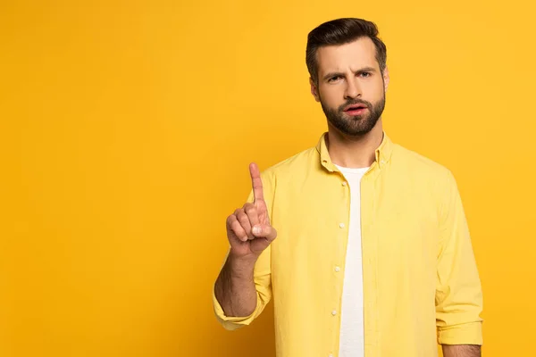 Homem pensativo apontando com o dedo no fundo amarelo — Fotografia de Stock