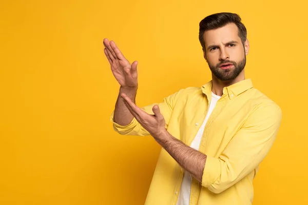 Uomo pensieroso che mostra gesto nel linguaggio dei segni su sfondo giallo — Foto stock
