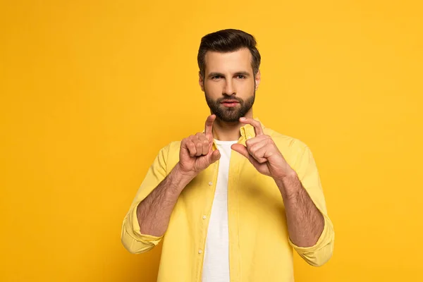 Homem barbudo mostrando gesto em linguagem surda e muda em fundo amarelo — Fotografia de Stock