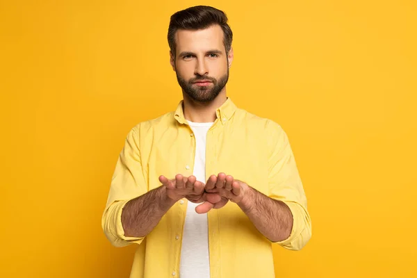 Young man using deaf and dumb language on yellow background — Stock Photo