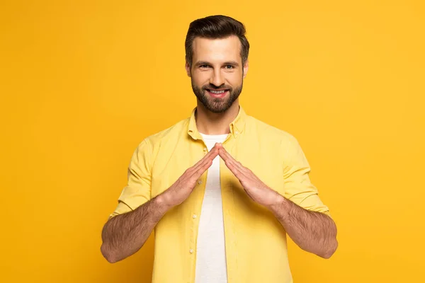 Sorrindo homem mostrando palavra casa em língua de sinais no fundo amarelo — Fotografia de Stock