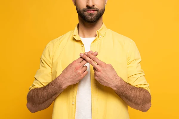 Vista recortada del hombre usando lenguaje de señas sobre fondo amarillo - foto de stock