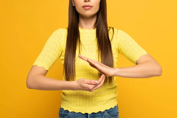 Vista recortada del gesto de la mujer mientras se utiliza el lenguaje sordo y mudo sobre fondo amarillo - foto de stock