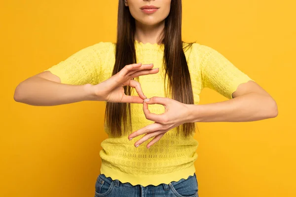 Обрезанный вид женщины, показывающей знак интерпретации в глухом и немом языке на желтом фоне — стоковое фото