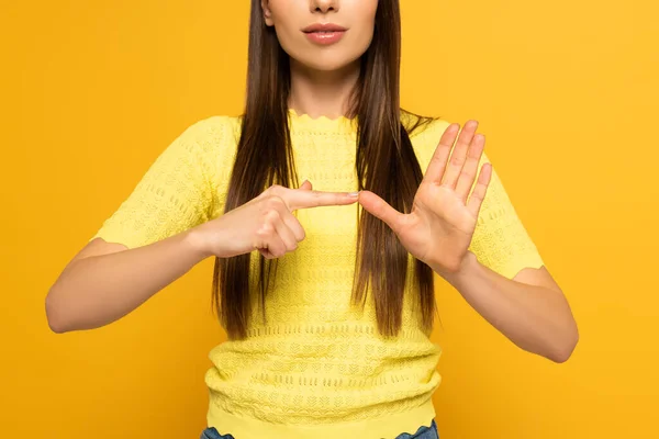 Cropped view of woman showing gesture from sign language on yellow background — Stock Photo