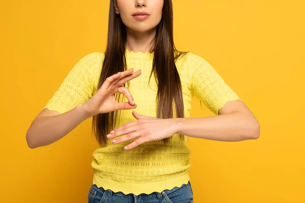 Vista recortada de la mujer usando lenguaje de señas sobre fondo amarillo - foto de stock