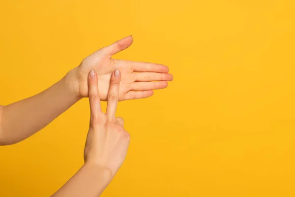 Vista cortada de mãos femininas mostrando gesto em linguagem surda e muda no fundo amarelo — Fotografia de Stock