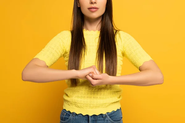 Cropped view of woman showing marriage sign in deaf and dumb language on yellow background — Stockfoto