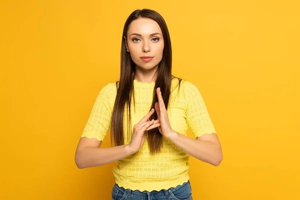 Mulher jovem mostrando gesto ao usar a linguagem surda e muda no fundo amarelo — Fotografia de Stock